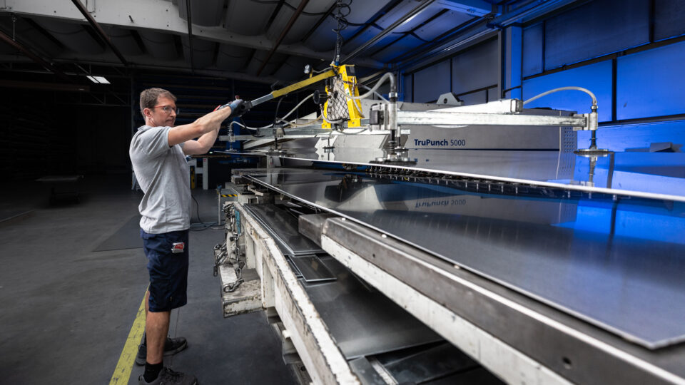 Employee at the punching and nibbling machine, loading sheets into the machine.